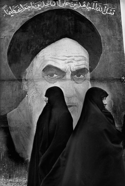 Women passing in front of a fresco representing ayatollah Khomeiny, Teheran, 1979